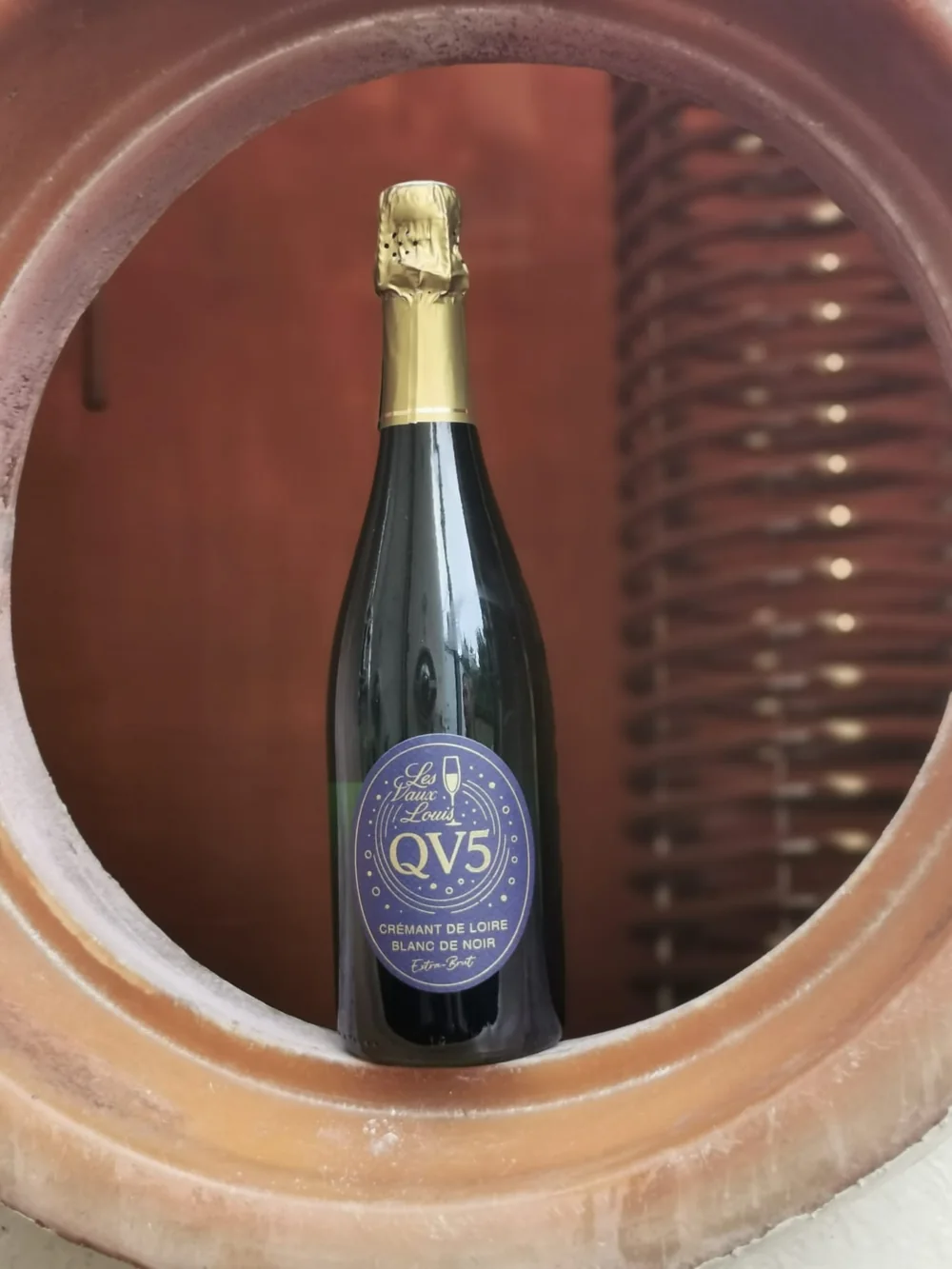 La bouteille de Crémant QV5 présentée dans une cuve du domaine